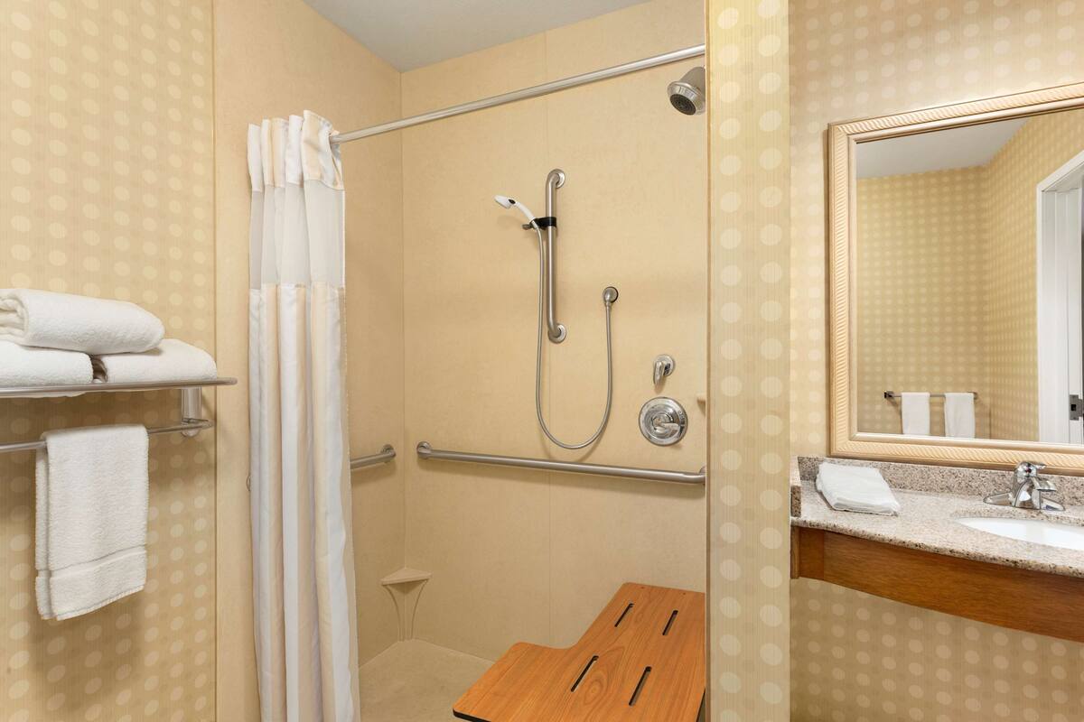 A bathroom with a shower, a sink, and a mirror.