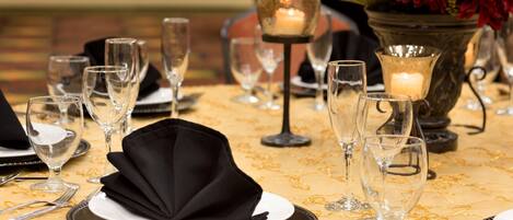 A table set for dining with clear glassware, black napkins, and a candle centerpiece.