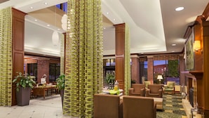 A lobby with seating areas, a fireplace, and a large window. - Hilton Garden Inn Bartlesville (Bartlesville)