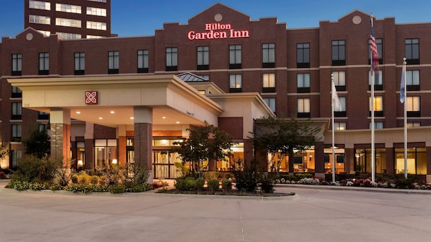 A Hilton Garden Inn with a brick facade, multiple windows, and an American flag. - Hilton Garden Inn Bartlesville (Bartlesville)