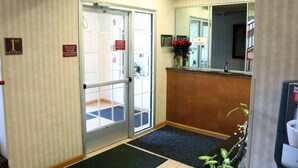 Et hotellobby med en receptionsdisk, et spejl, en dør med skiltet "1st Central" og et skilt der viser udgangen.