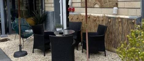 An outdoor seating area with wicker furniture and thatched umbrellas, a bar area, and a stone-tiled floor.