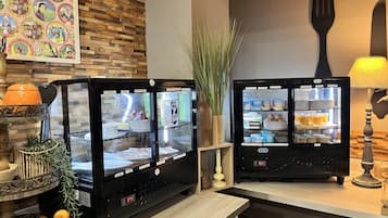 Two self-service beverage dispensers with various drink options, a decorative wall with vintage postcards, and a rustic wooden counter.
