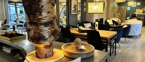 A modern dining area with a birch wood centerpiece, a chessboard, and contemporary furniture.