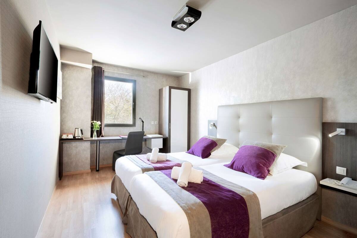 Una habitación de hotel moderna con una cama grande, un escritorio, una silla y un televisor.
