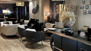 Un moderno vestíbulo de hotel con una recepción, zona de estar y un bar.