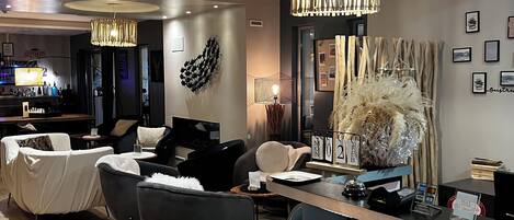 A modern hotel lobby with a reception desk, seating area, and a bar.