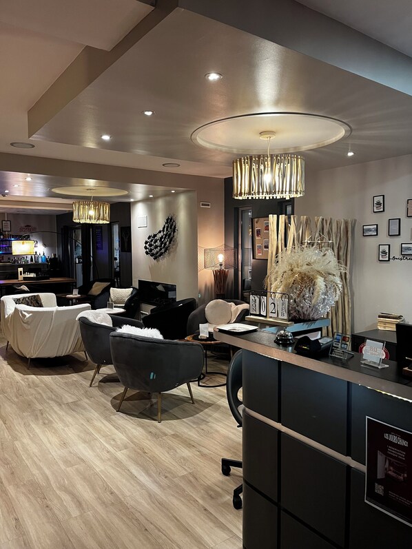A modern hotel lobby with a reception desk, seating area, and a bar. - Best Western La Mare o Poissons (Ouistreham)