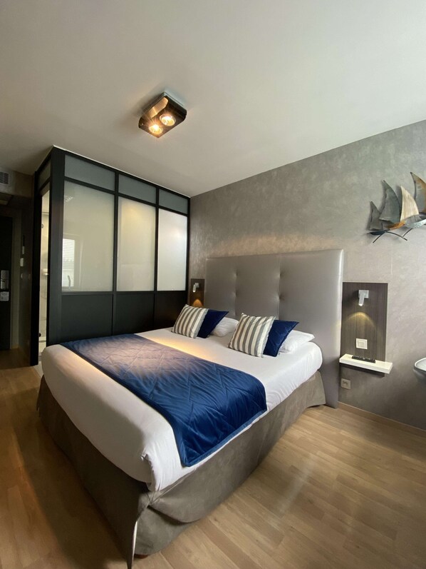 Un dormitorio moderno con una cama grande, cabecera, mesita de noche y lámpara de pared.