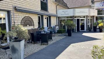 Un hôtel doté d’une terrasse, d’un espace de réception et d’un panneau indiquant la présence d’un bar et d’une piscine chauffée.