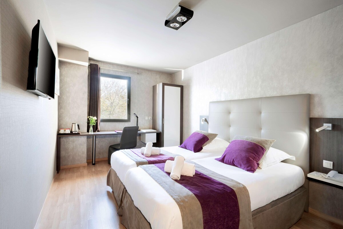 Una habitación de hotel moderna con dos camas, un escritorio y televisión.