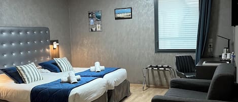 A modern hotel room with a large bed, a sofa, a desk, and a window with curtains.