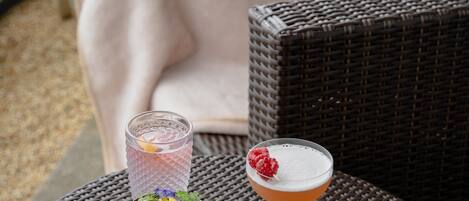 A wicker table with two drinks and a small salad bowl.