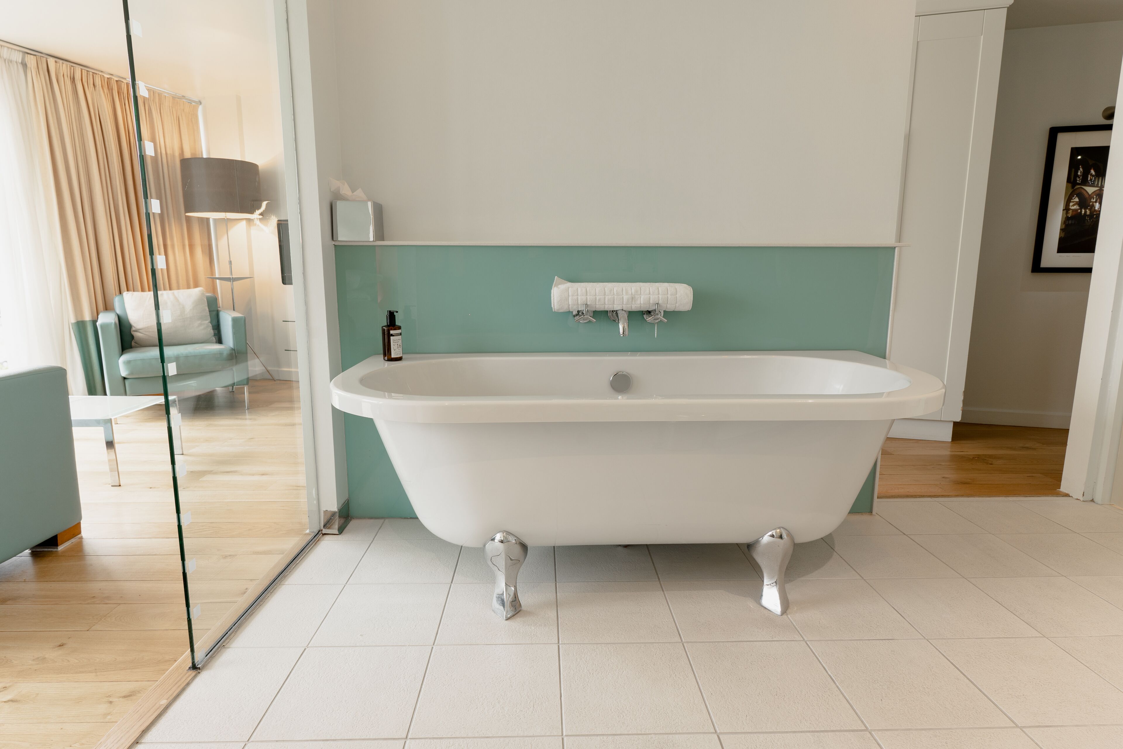 A modern bathroom with a freestanding bathtub, a glass shower enclosure, and a teal accent wall.