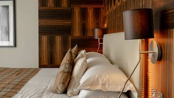 A neatly made bed with pillows, a wall-mounted lamp, and a wooden panel wall.