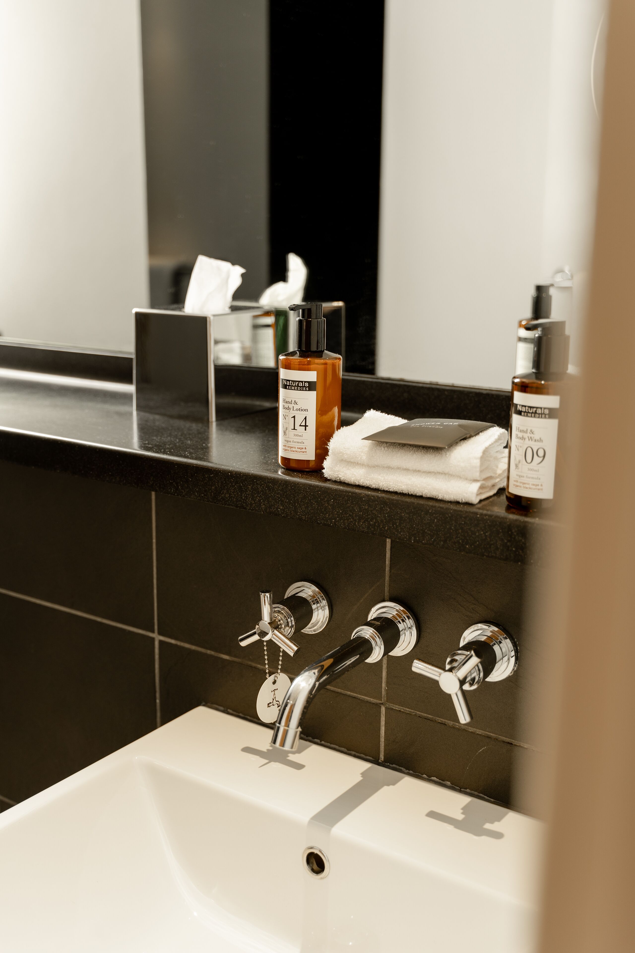Un lavabo de salle de bain avec deux robinets, un miroir et des articles de toilette posés sur le comptoir.