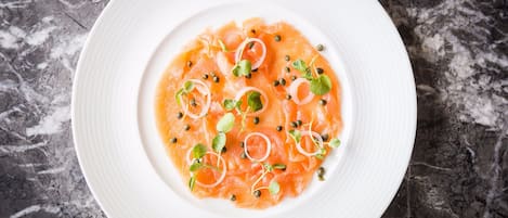 Un plato blanco con salmón y guarniciones sobre una superficie de mármol.