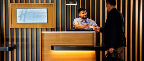 Un mostrador de recepción en Holiday Inn Express, con un diseño moderno, una señal enmarco y una lámpara colgante negra.