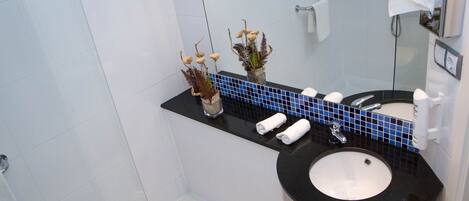 Un baño moderno con un lavamanos negro, azulejos blancos y un salpicadero revestido de azul.