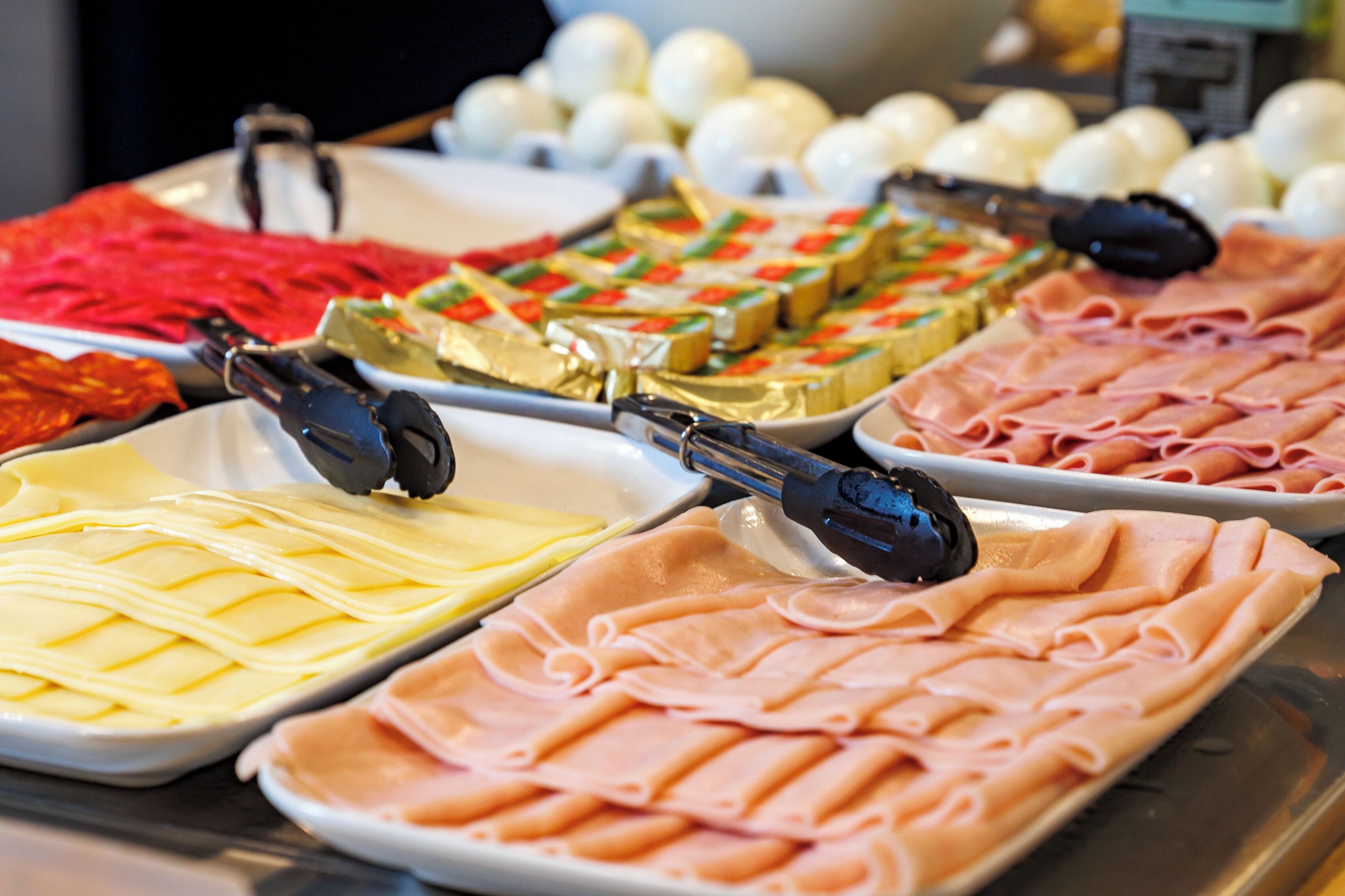 A buffet with various food items including sliced meats and cheeses.