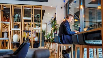 Een modern interieur met houten meubels, een zithoek en een persoon die een laptop gebruikt.
