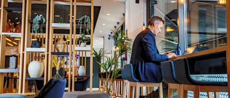 A modern interior with wooden furniture, a seating area, and a person using a laptop.