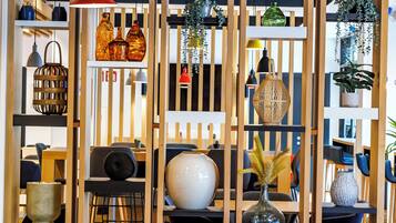 A modern interior with wooden partitions, shelves with decorative items, and a dining area with chairs and tables.