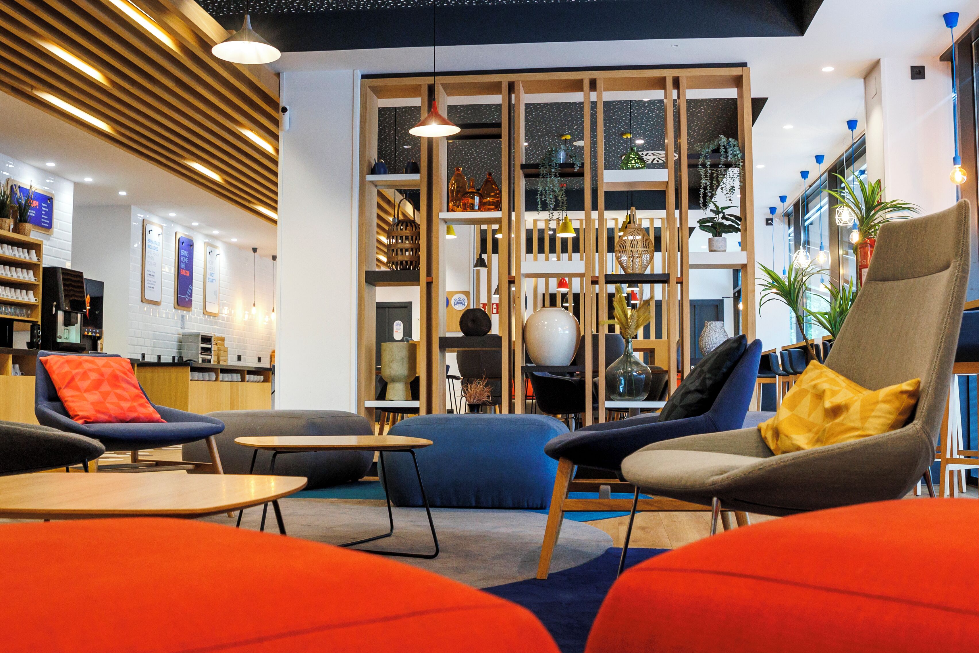 Un moderno espacio lounge con asientos, mesas y una pared decorativa con plantas e iluminación.
