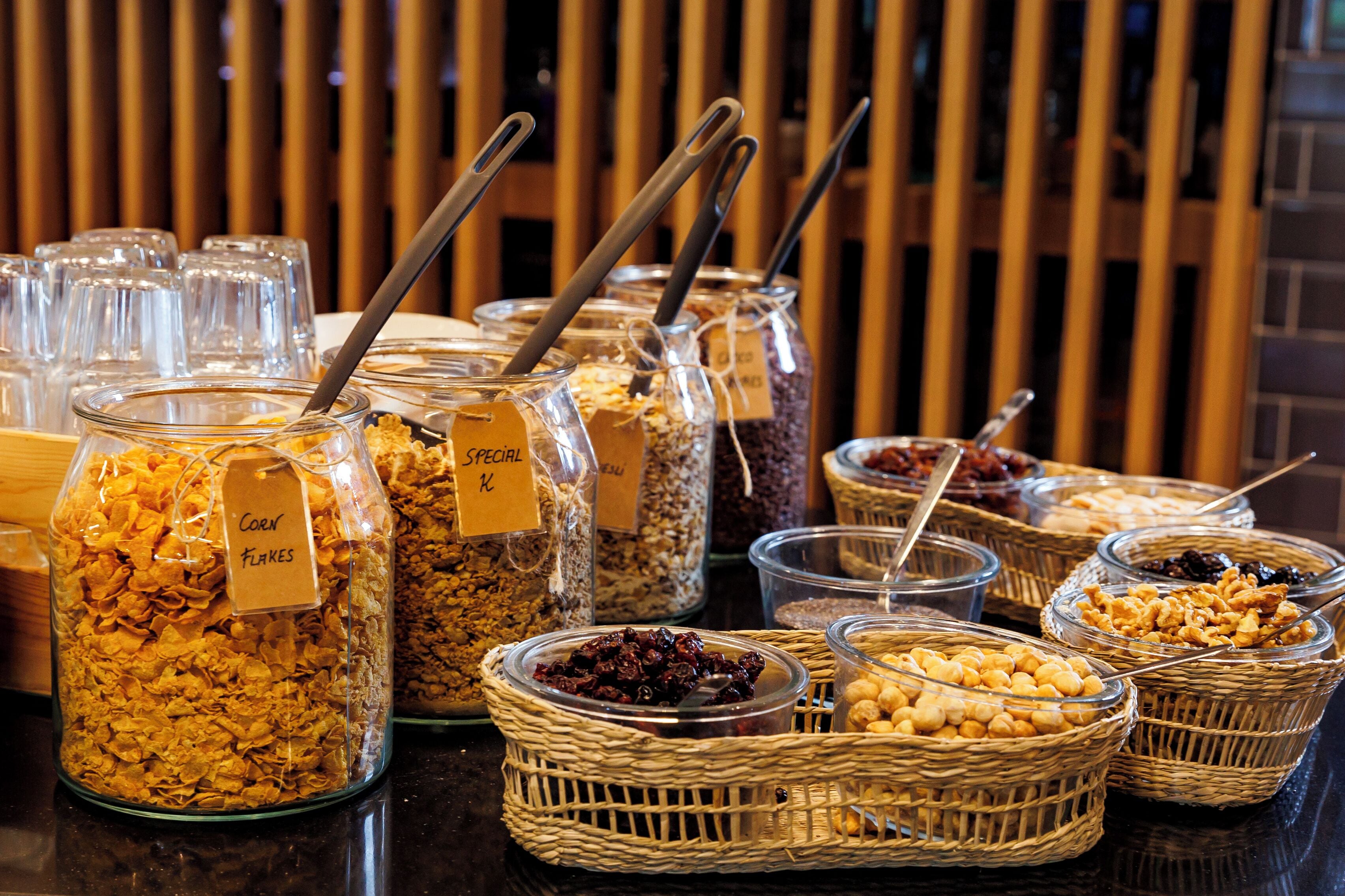 Diversos alimentos en frascos y cestas, como cereales y frutos secos, con etiquetas que identifican sus tipos.
