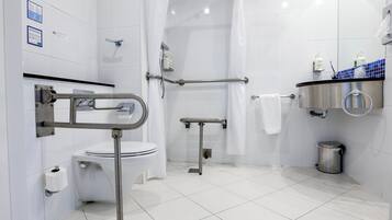 A modern bathroom with a toilet, bidet, and shower area, equipped with grab bars and a handrail.