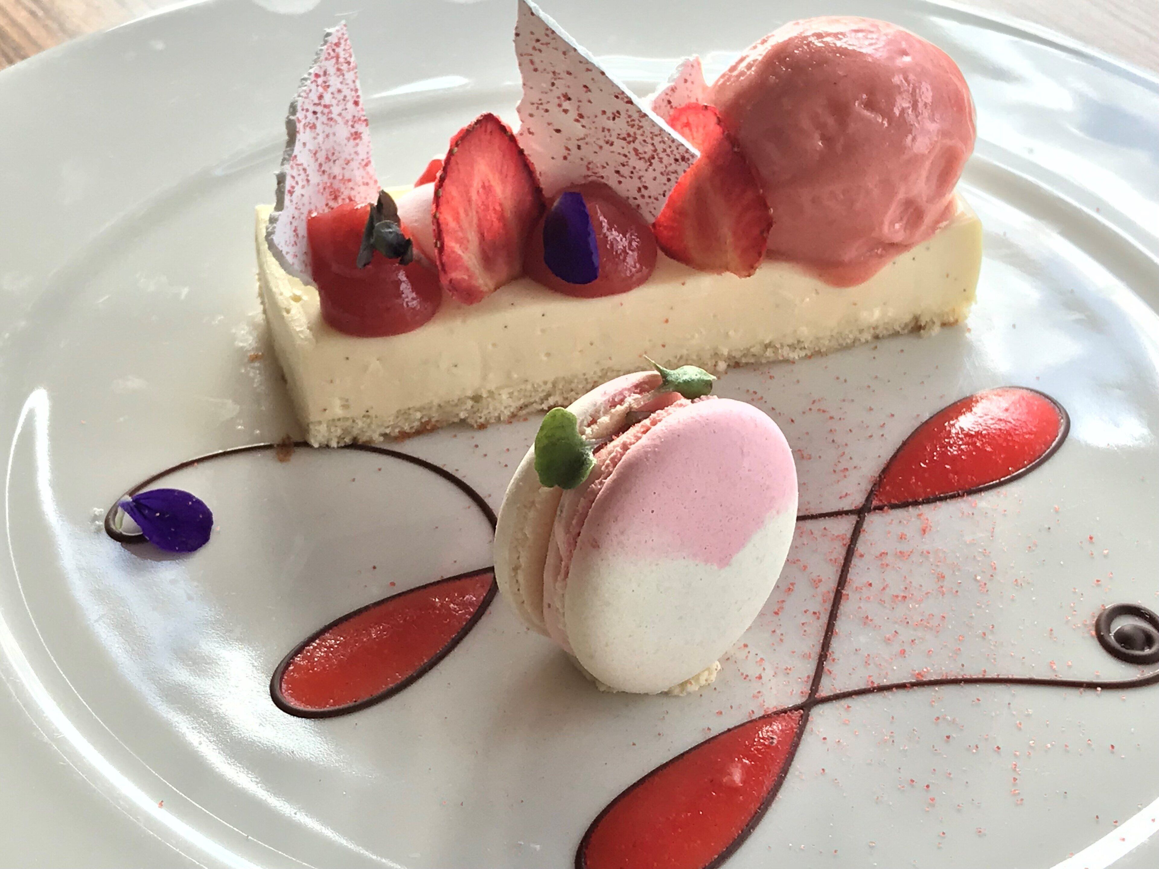 A dessert with ice cream, strawberries, and macarons on a plate.