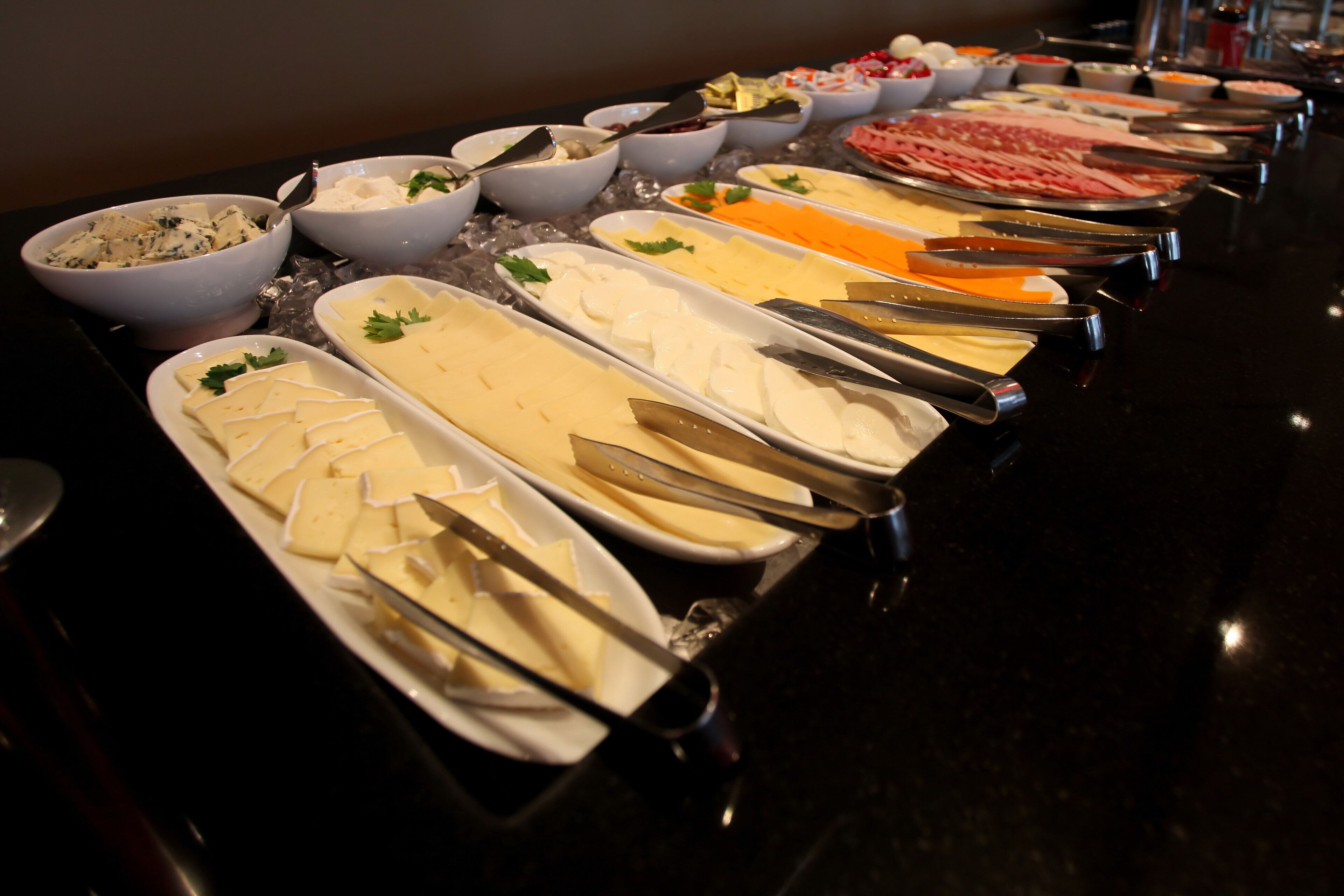 A buffet with various food items including cheese, meats, and salads.