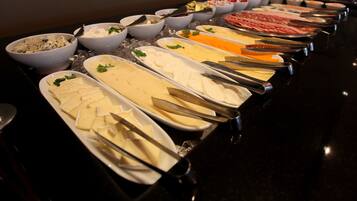 A buffet with various food items including cheese, meats, and salads.