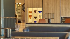 A modern interior with a seating area, a glass display of decorative bowls, and a contemporary lamp. - Crowne Plaza Reading by IHG (Reading)