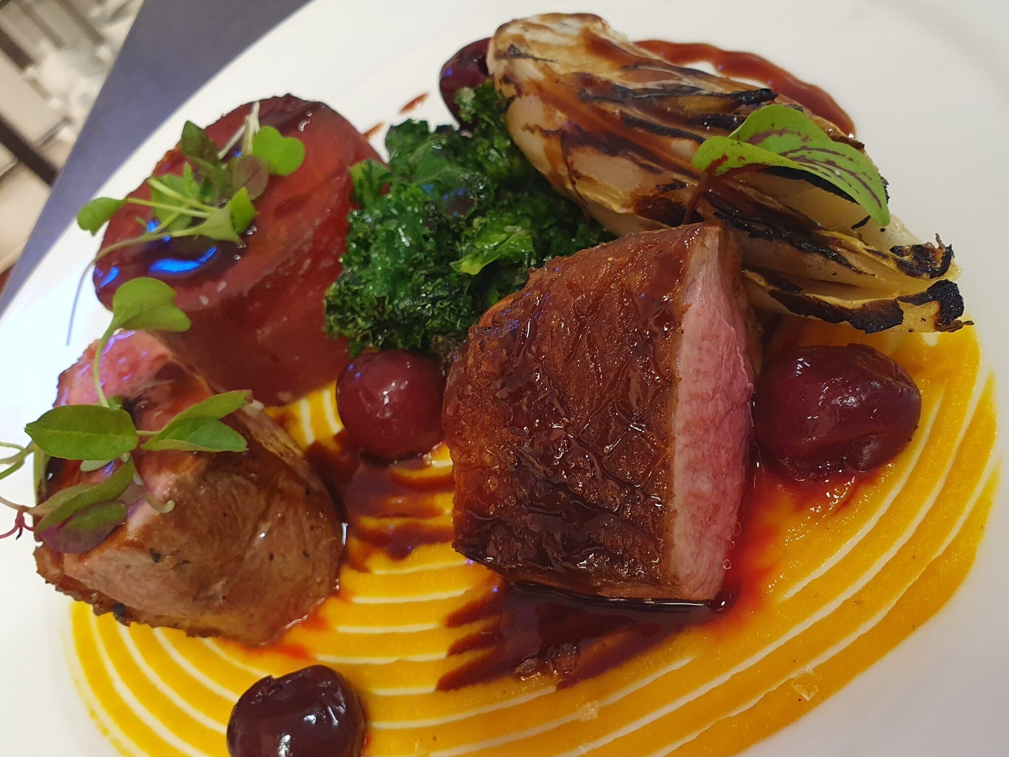 A plated dish with various food items including meat, vegetables, and a sauce.