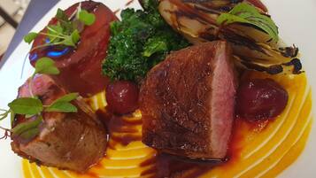 A plated dish with various food items including meat, vegetables, and a sauce.