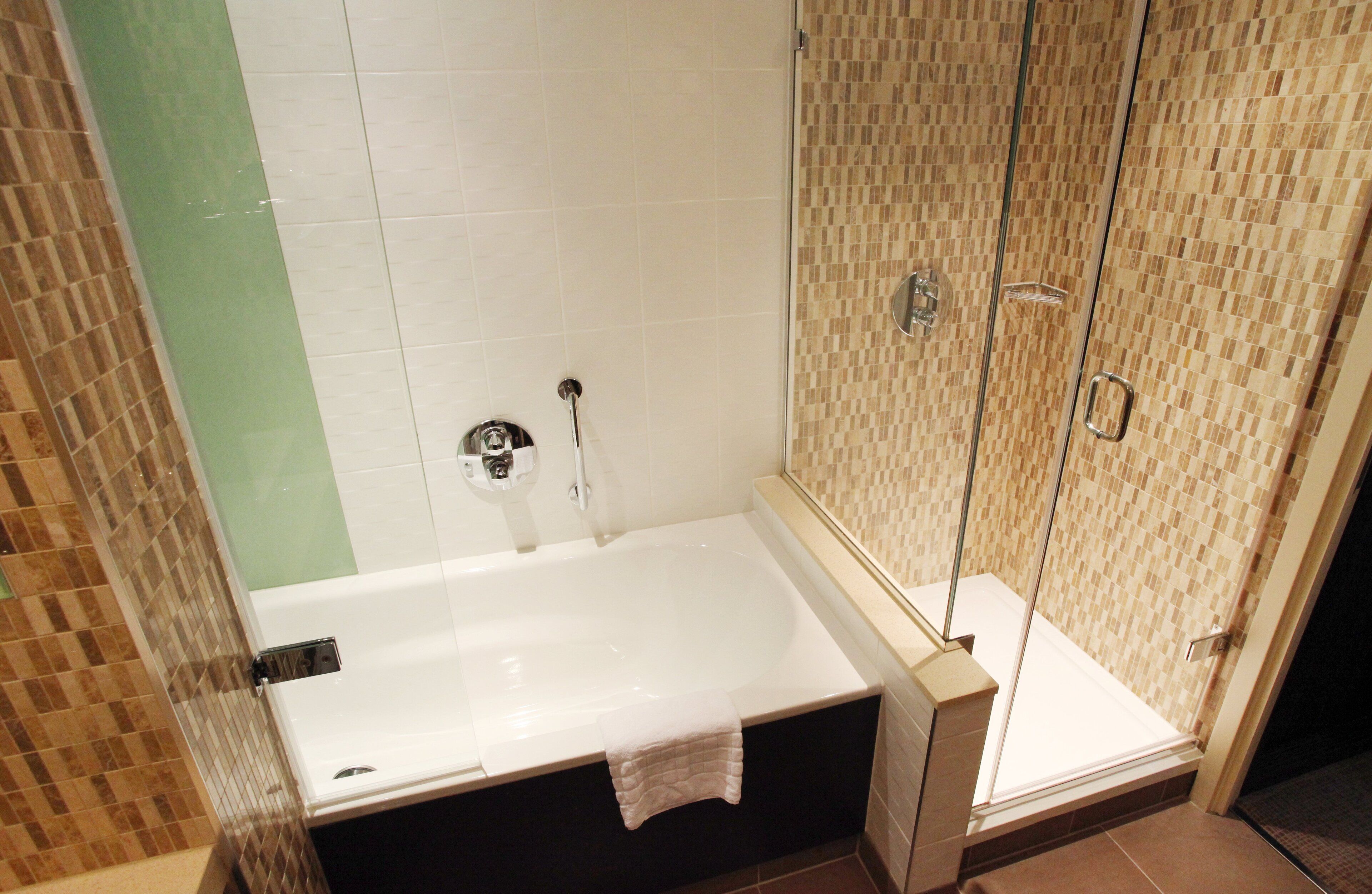 Un baño moderno con ducha de vidrio, bañera blanca y piso de baldosas.