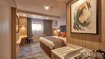 Een hotelkamer met een bed, een bureau, een stoel, een koffiezetapparaat en een lijst met abstracte kunst.