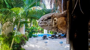 A pool area with lounge chairs, a rock formation with 'SPA' carved into it, and lush tropical plants. - Bric Hotel & Spa (Playa del Carmen)