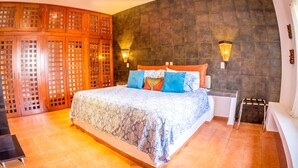 Un dormitorio con una cama grande, un armario de madera y dos lámparas de pared.
