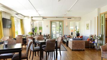 A spacious room with a dining area, seating, and a bar area with bottles.