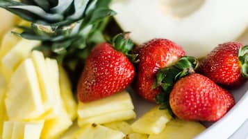 A plate with sliced pineapple and strawberries.