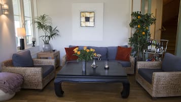 A living room with a sofa set, a coffee table, a potted plant, and a wall-mounted artwork.