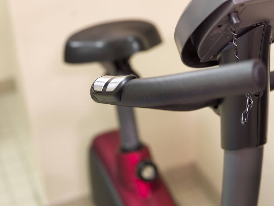 Ein Detailbild von einem stehenden Heimtrainer mit Metalllenker und roter Sattel.