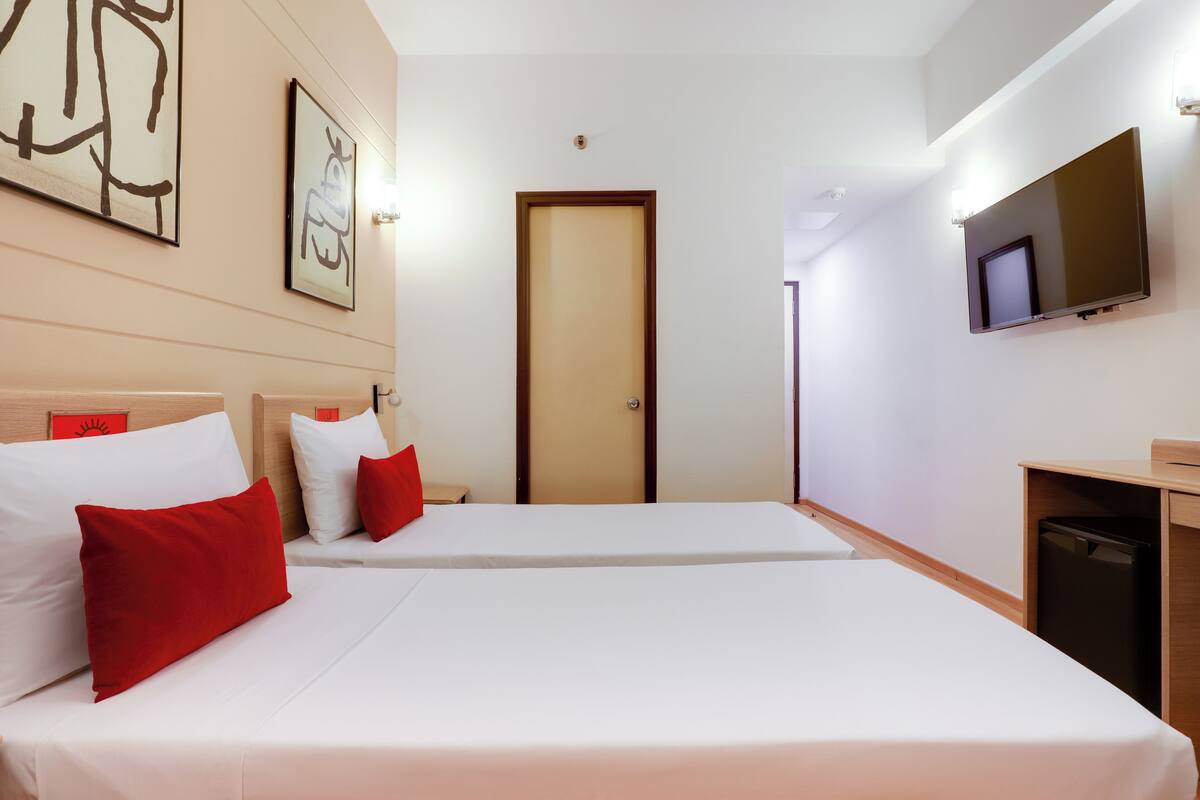A hotel room with two beds, a TV, and artwork on the walls.