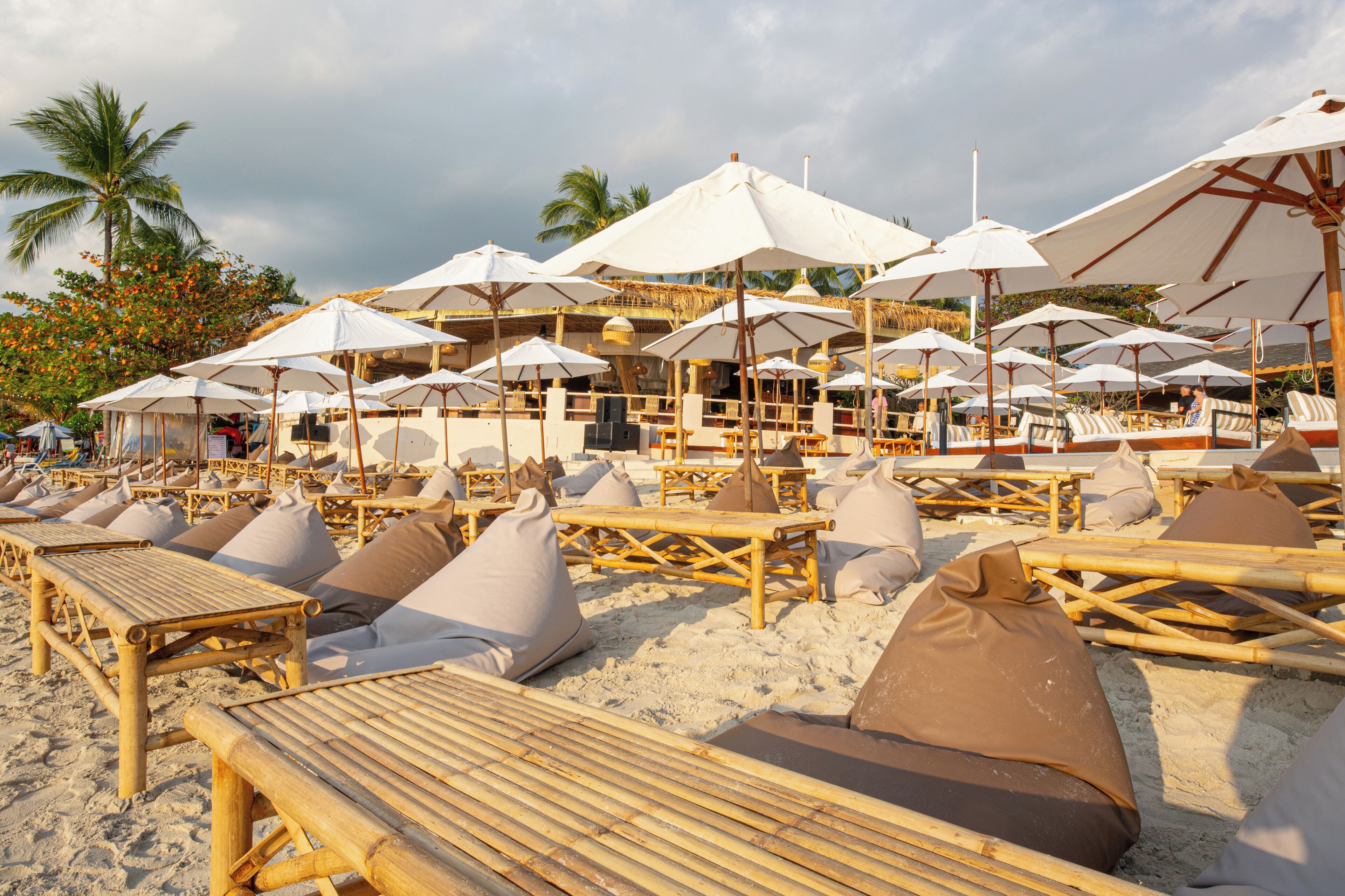 A beachside resort with bamboo lounge chairs and white umbrellas.