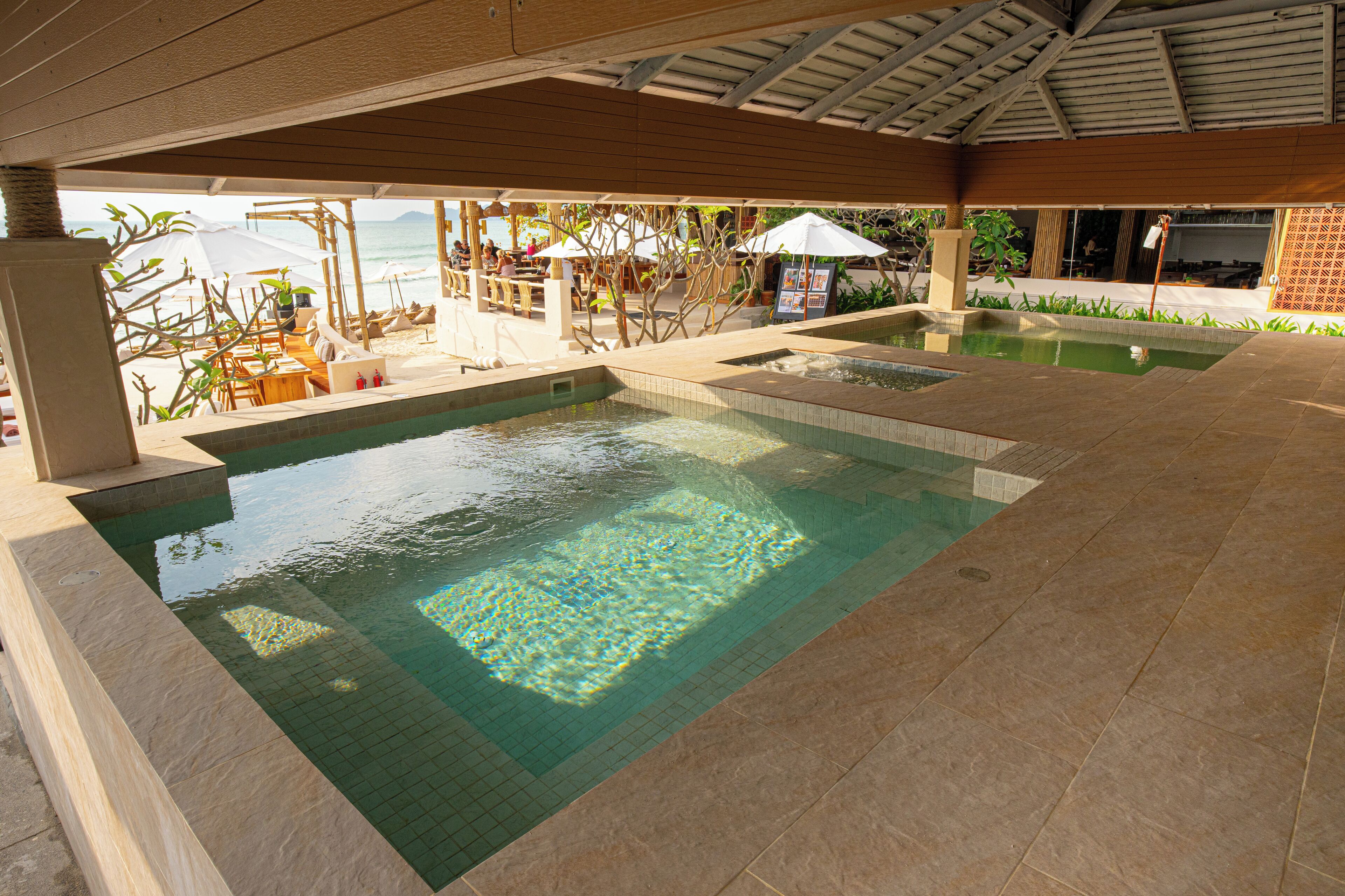 Ein Poolbereich mit mehreren Pools, Liegestühlen und Sonnenschirmen.