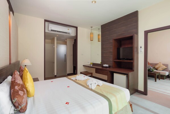 A hotel room with a bed, a desk, a TV, and a seating area. - Al's Resort (Koh Samui)