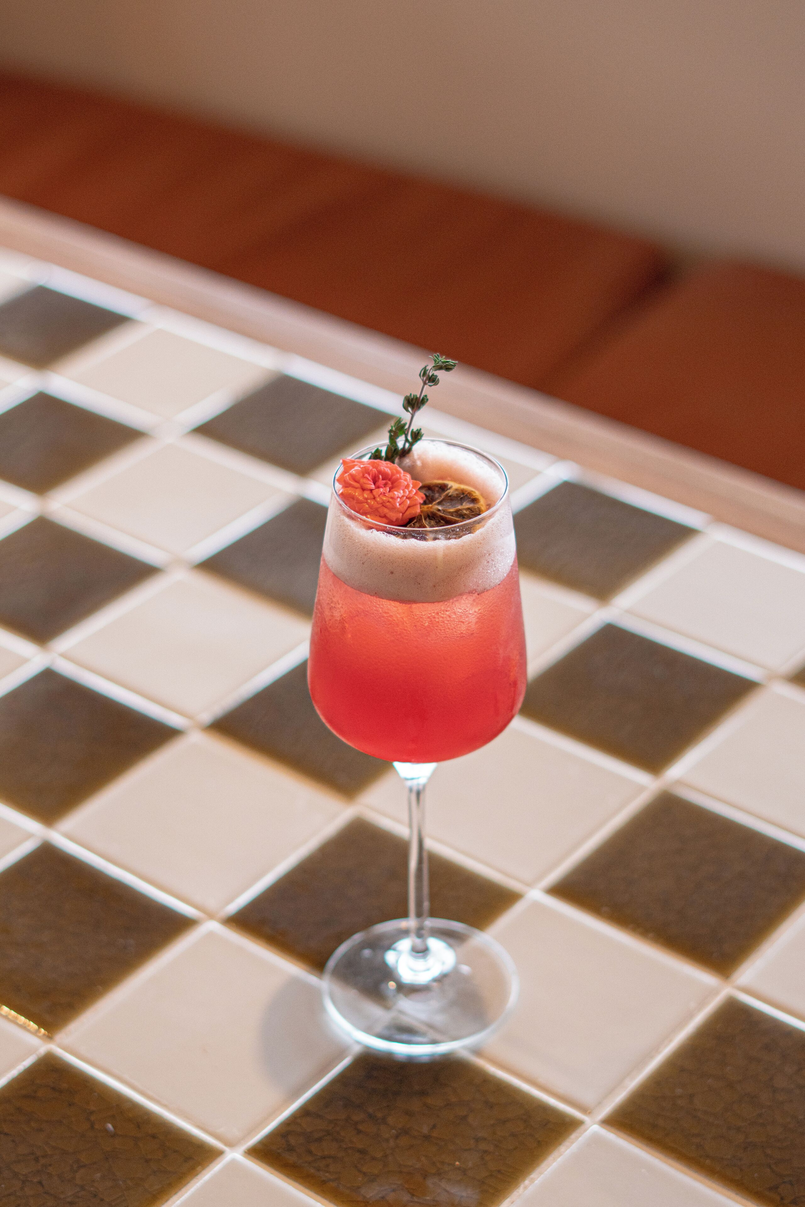 A cocktail in a glass with a garnish on a tiled surface.