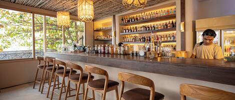 A bar area with wooden chairs, a bar counter, and shelves of liquor bottles.